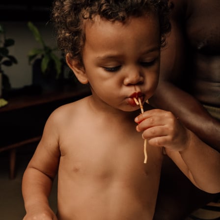 Baby boy eating pasta, with dermatologist-tested, hypoallergenic Huggies® Skin Essentials™ wipes 