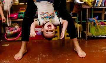 Parent holding an excited toddler upside down in the air
