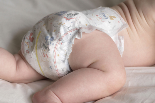 A baby lays on its tummy wearing a Huggies Snug and Dry Diape
