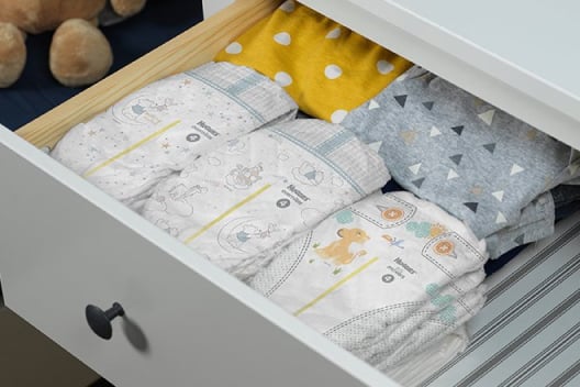 The top drawer of a white dresser is pulled out to display multiple Huggies Overnites Diapers with wetness indicators